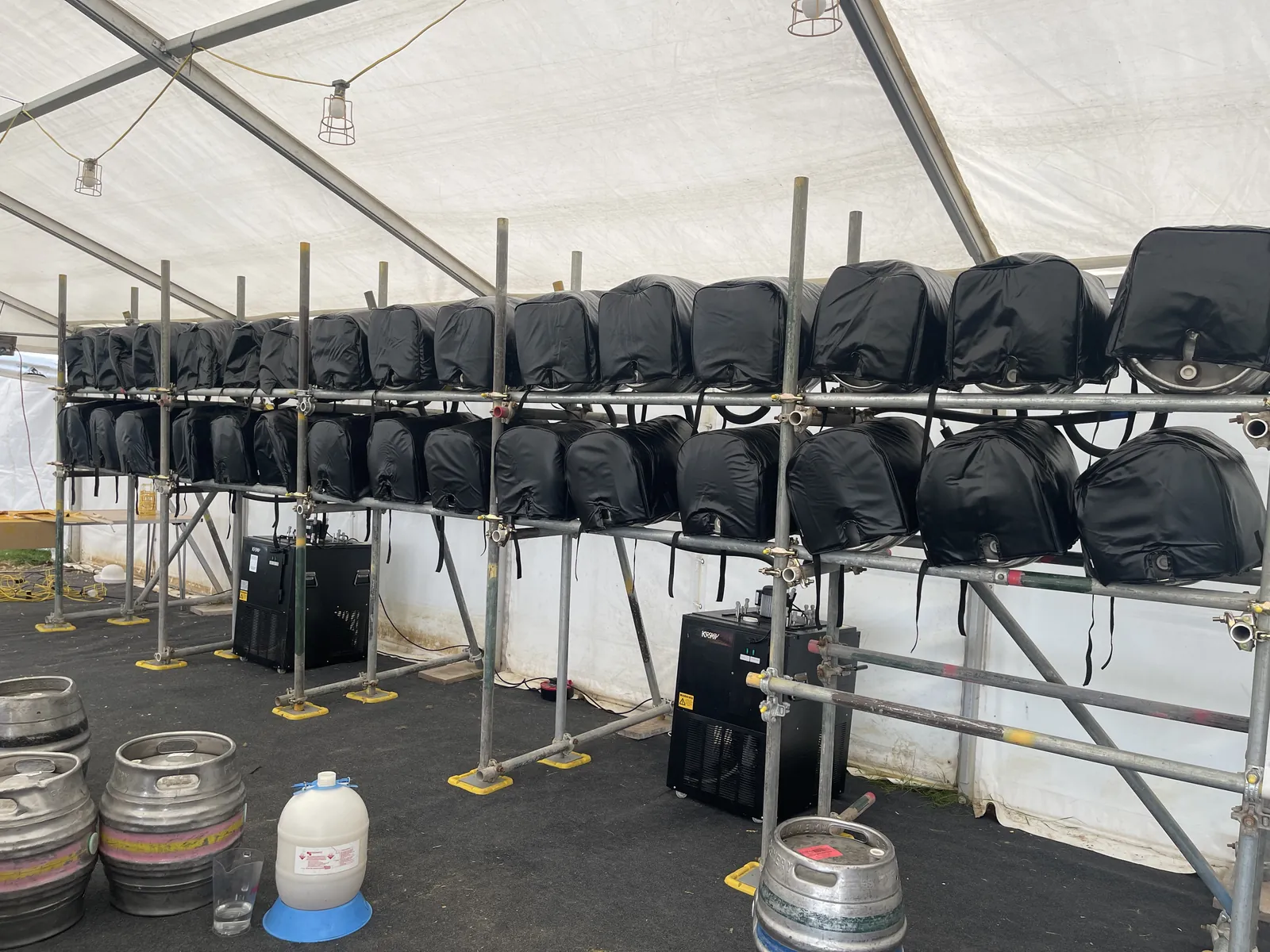 Two tiers of casks in actively cooled cask jackets on scaffold stillage, with python coolers underneath, in an Oxfordshire ale festival marquee