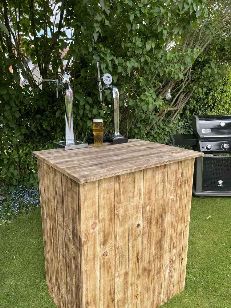 Rustic wooden keg bar with two taps on a lawn beside a barbecue at a Bristol garden party