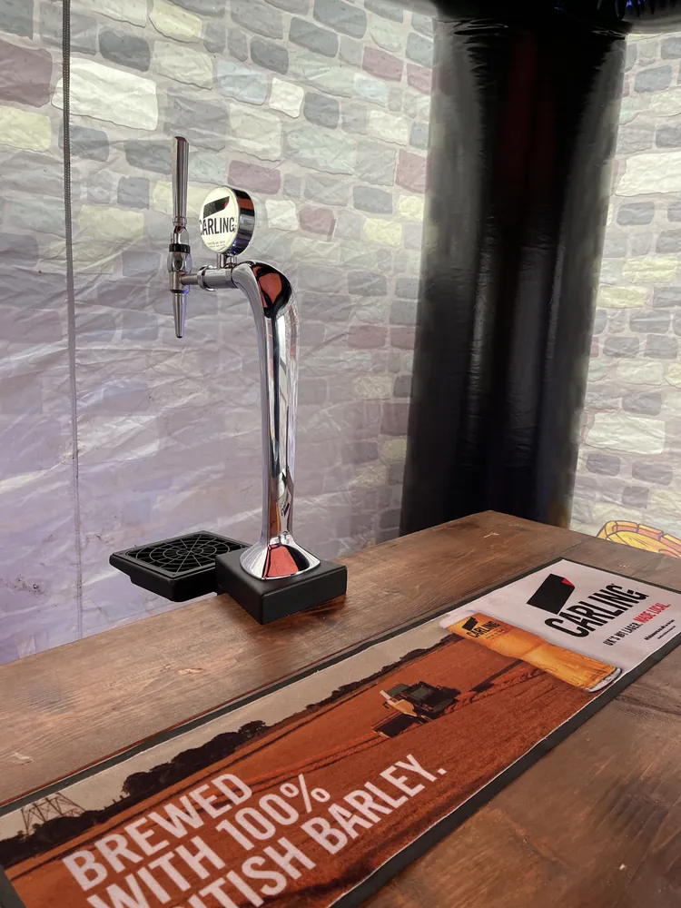 Single Carling font on a wooden bar top inside a brick-print party tent in Bromsgrove