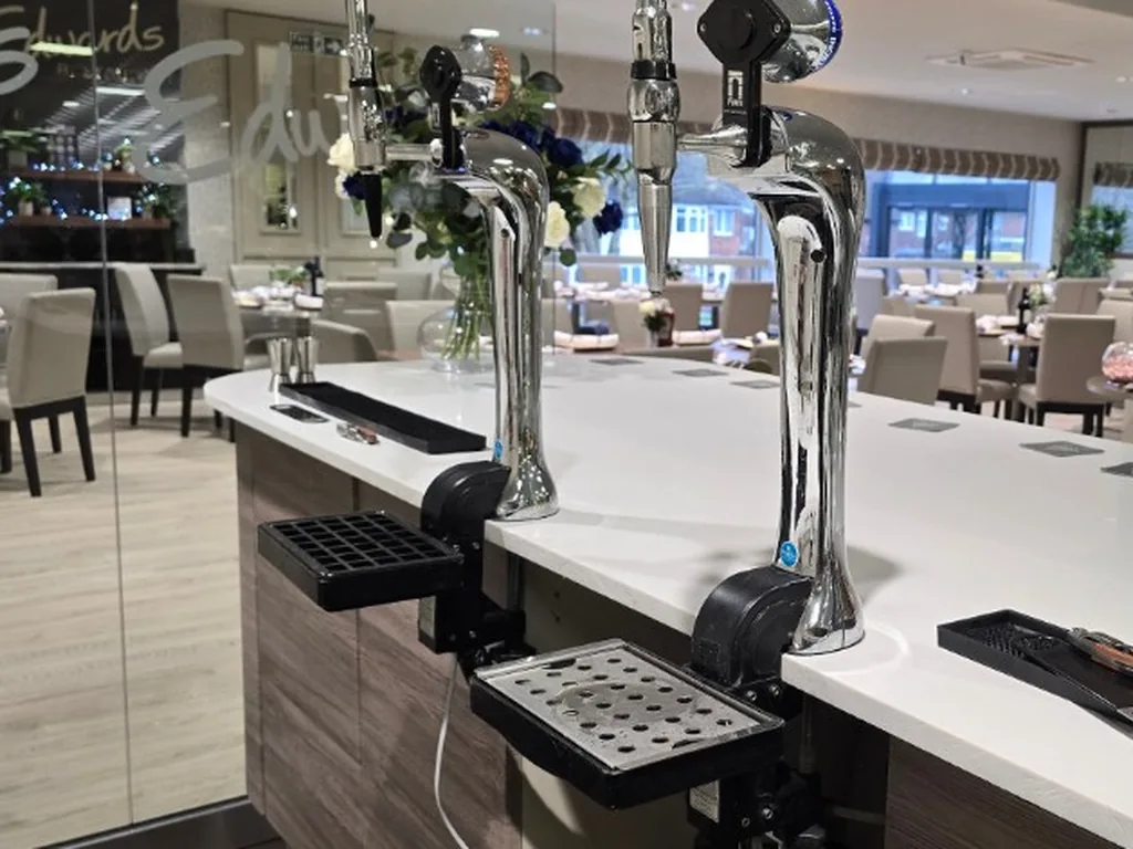 Two chrome clamp-on taps on a white counter for a corporate bar in Birmingham