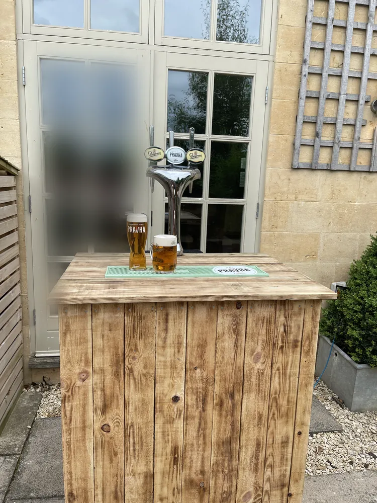 Rustic wooden keg bar with a three-way Staropramen and Pravha font outside a Cotswold stone house for a stag do