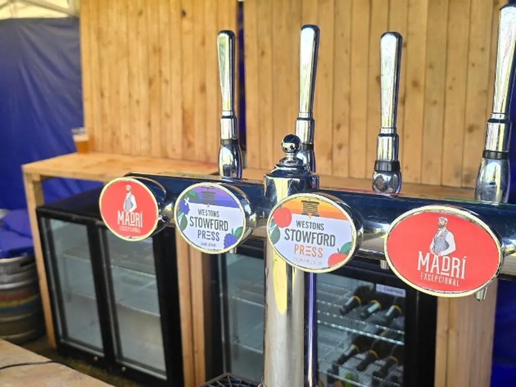 Glass-front bottle fridges behind a four-tap font at a Stratford-upon-Avon festival