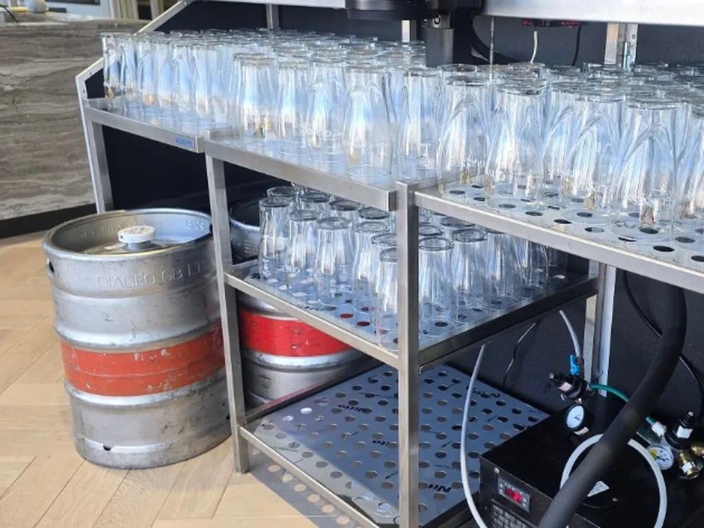 Kegs, flash cooler, gas and Guinness glasses on the service side of a stainless portable bar in a London office