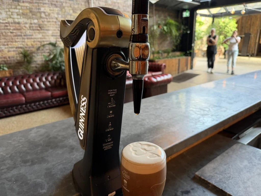 Poured pint of Guinness with a shamrock on the head, beside the harp font at 100 Barrington, Brixton