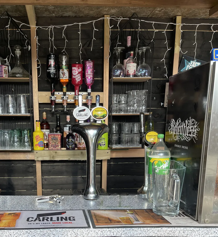 Full garden pub bar in Malvern with a Carling and Thatchers font, optics, glass shelves and fairy lights
