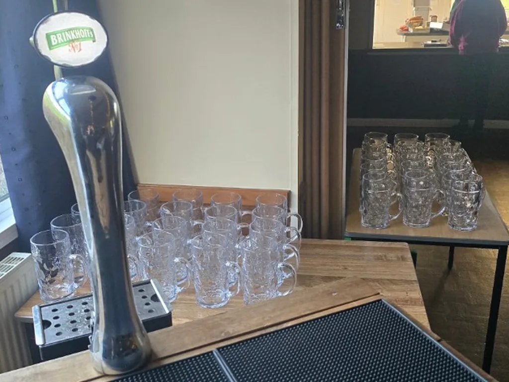 Dimpled beer steins lined up beside a Brinkhoff's tap at an Oktoberfest bar in Devon
